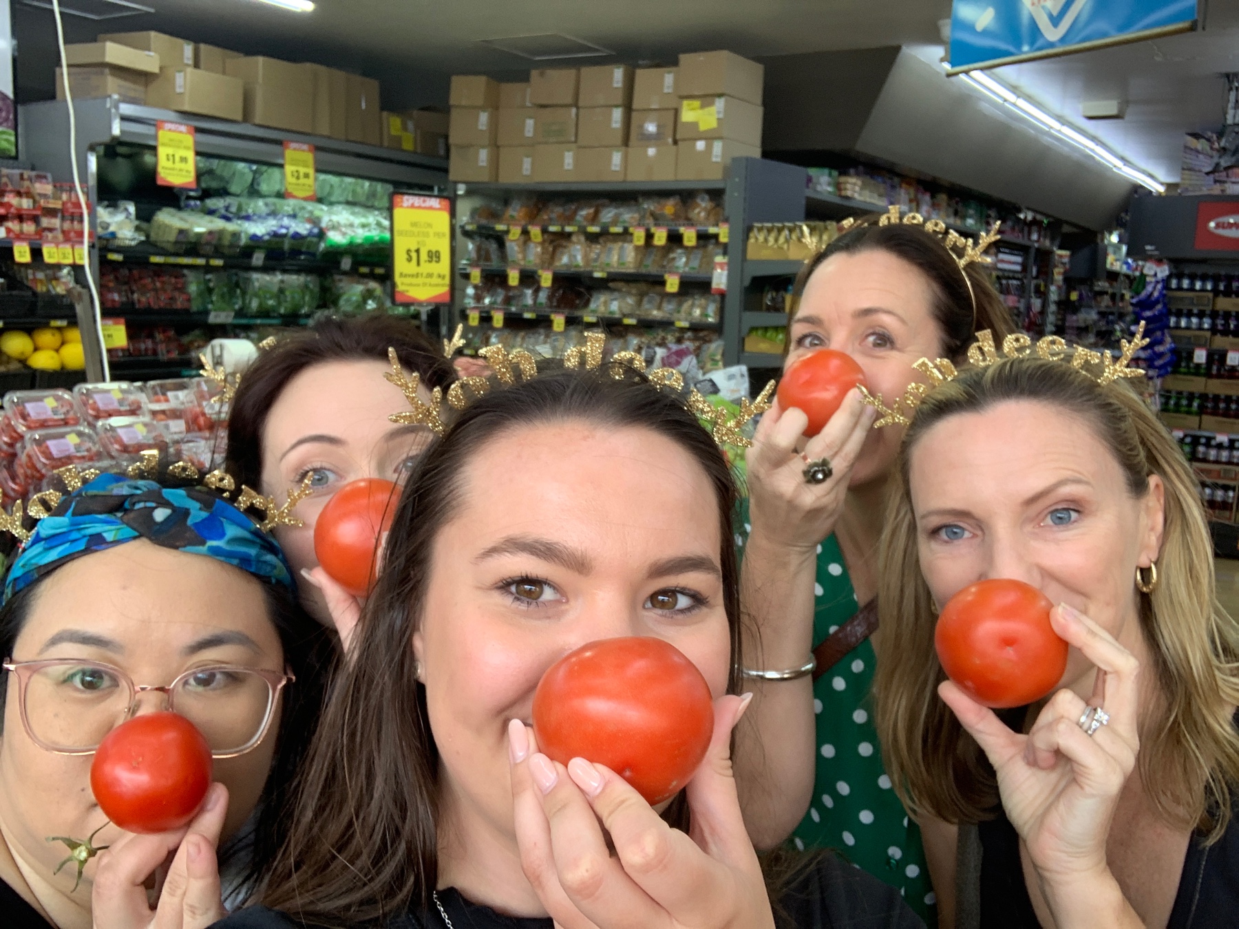 Group of women wearing reindeer headbands and holding tomatoes as Rudolph noses during a Christmas scavenger hunt on the Gold Coast.
