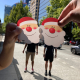 Hands holding Santa face cutouts during a Christmas scavenger hunt on the Gold Coast city streets.